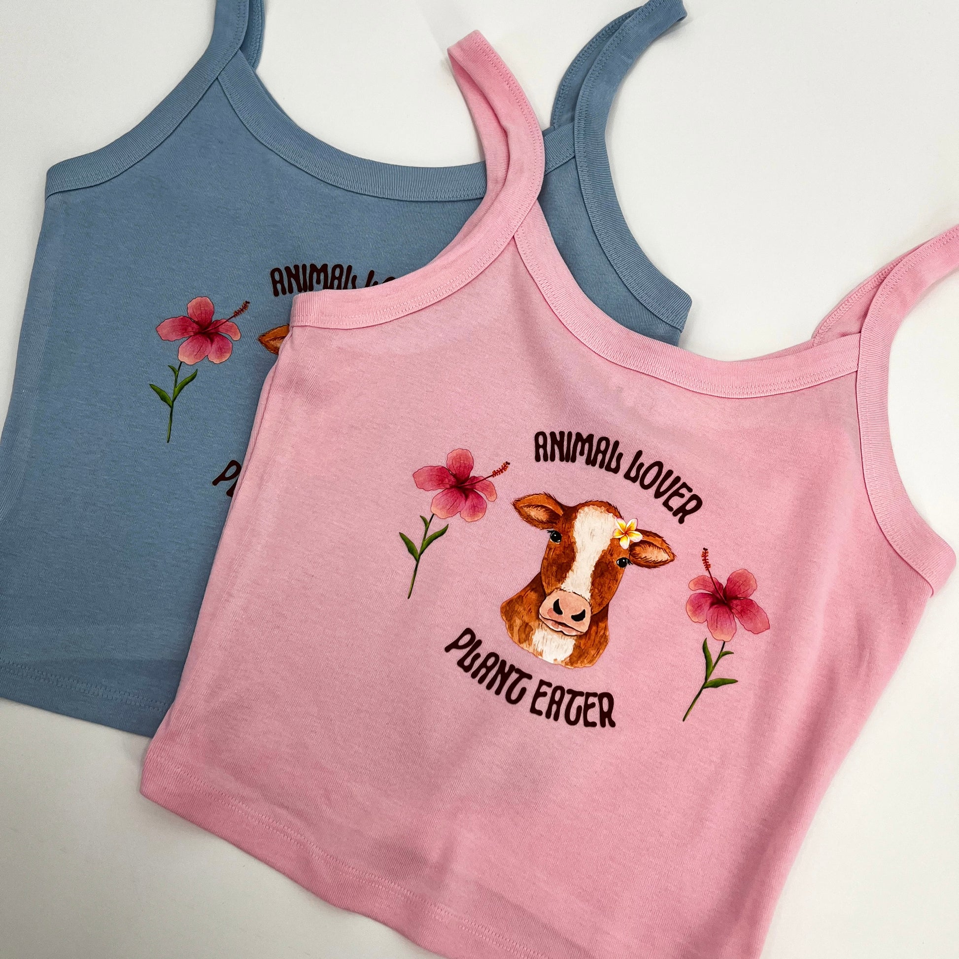 Cute pink and blue crop top featuring vegan activism graphic of a cow with flowers and text animal lover plant eater