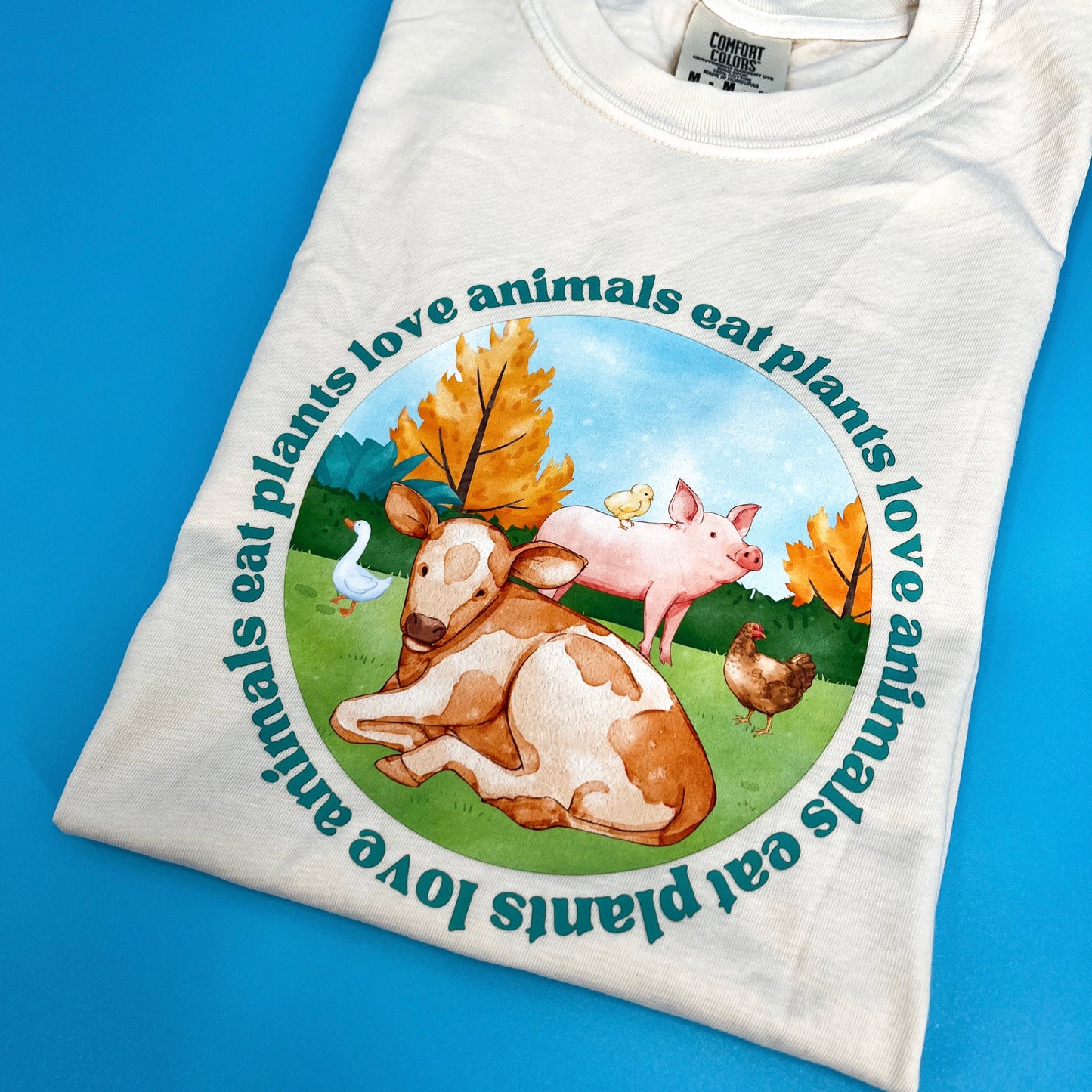 Natural colored vegan activism tee featuring farm animals graphic and text Love Animals Eat Plants