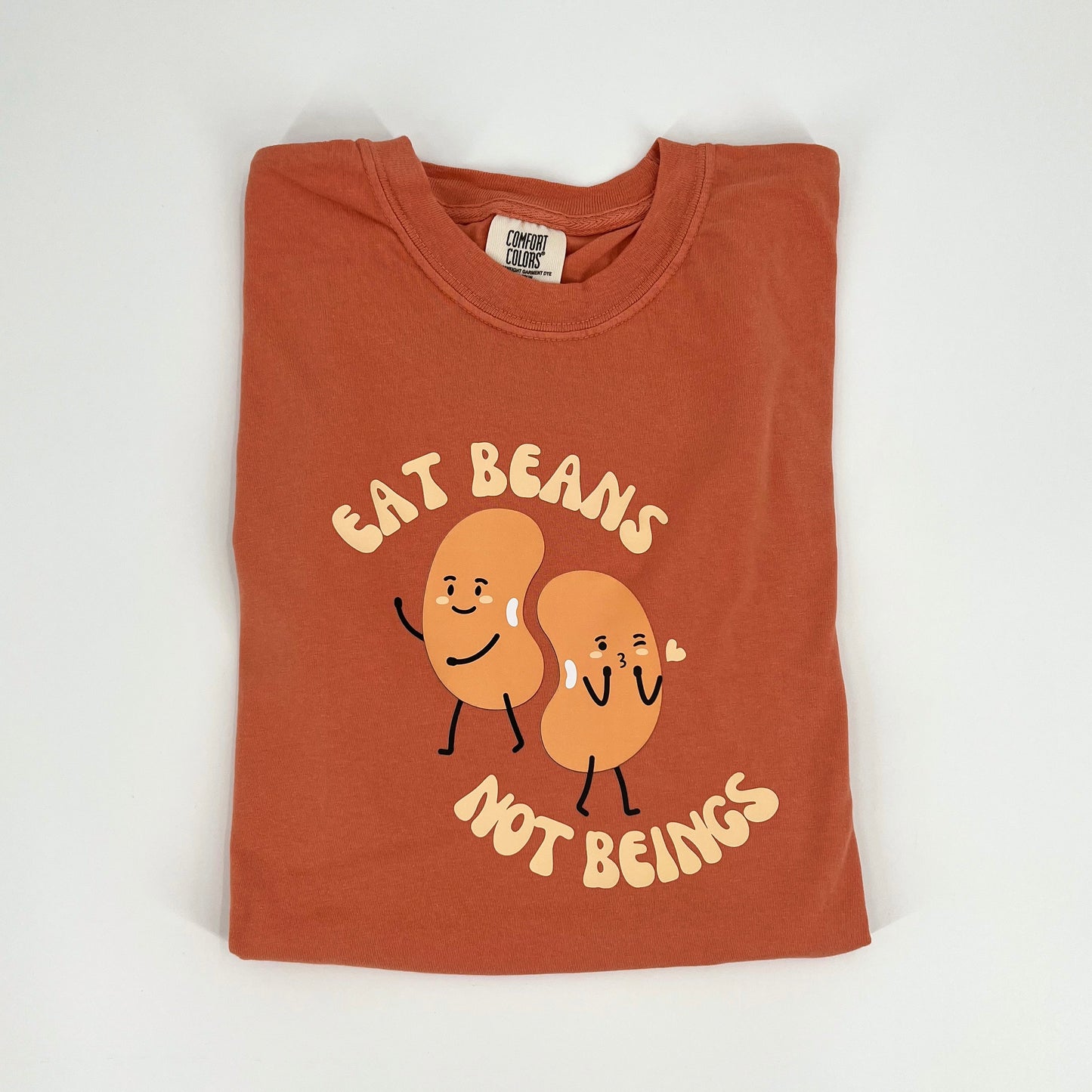 Terracotta colored vegan activism shirt featuring "Eat Beans Not Beings" graphic